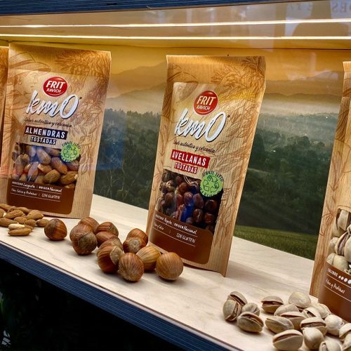 Expositor de madera con bolsas de frutos secos Frit Ravich de la gama km0, mostrando almendras, avellanas y pistachos tostados