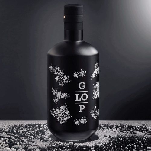 Diseño de botella negra mate para la bebida Glop, decorada con ilustraciones blancas de ramas de enebro